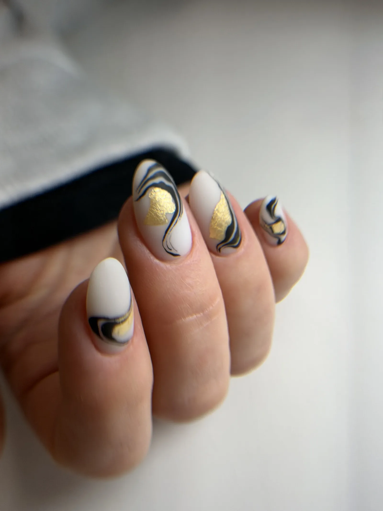 Matte cream nails with black and gold abstract swirls
