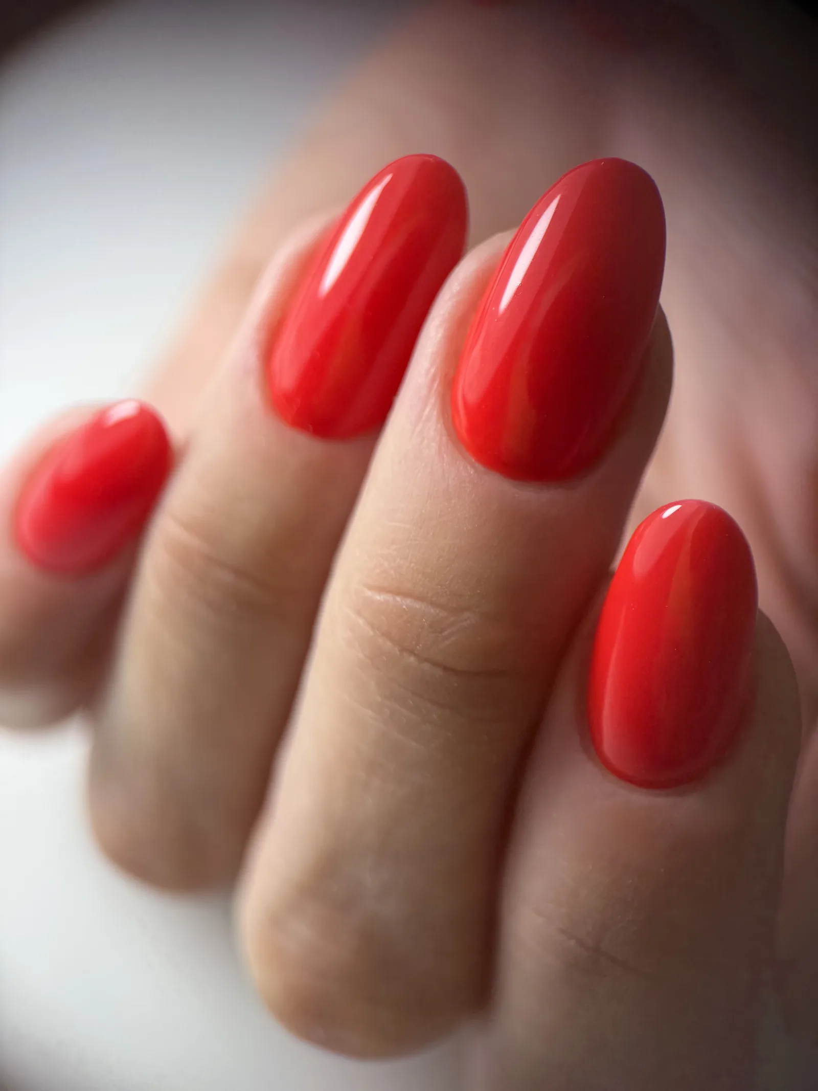 Close-up of glossy red almond nails with a clean cuticle line