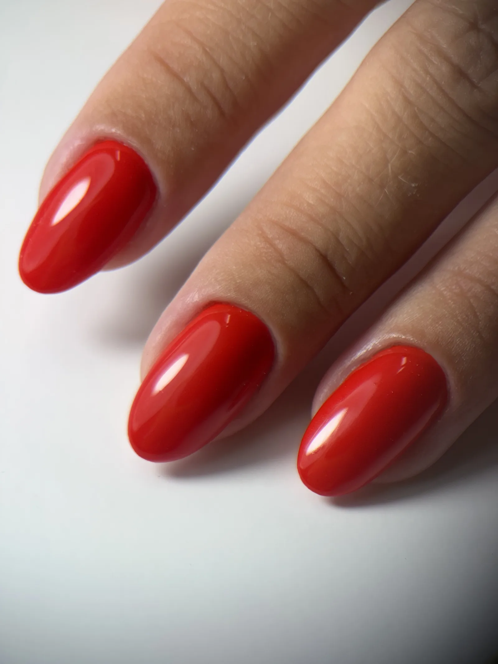 Close-up of red almond gel nails with a seamless cuticle edge after a Russian manicure